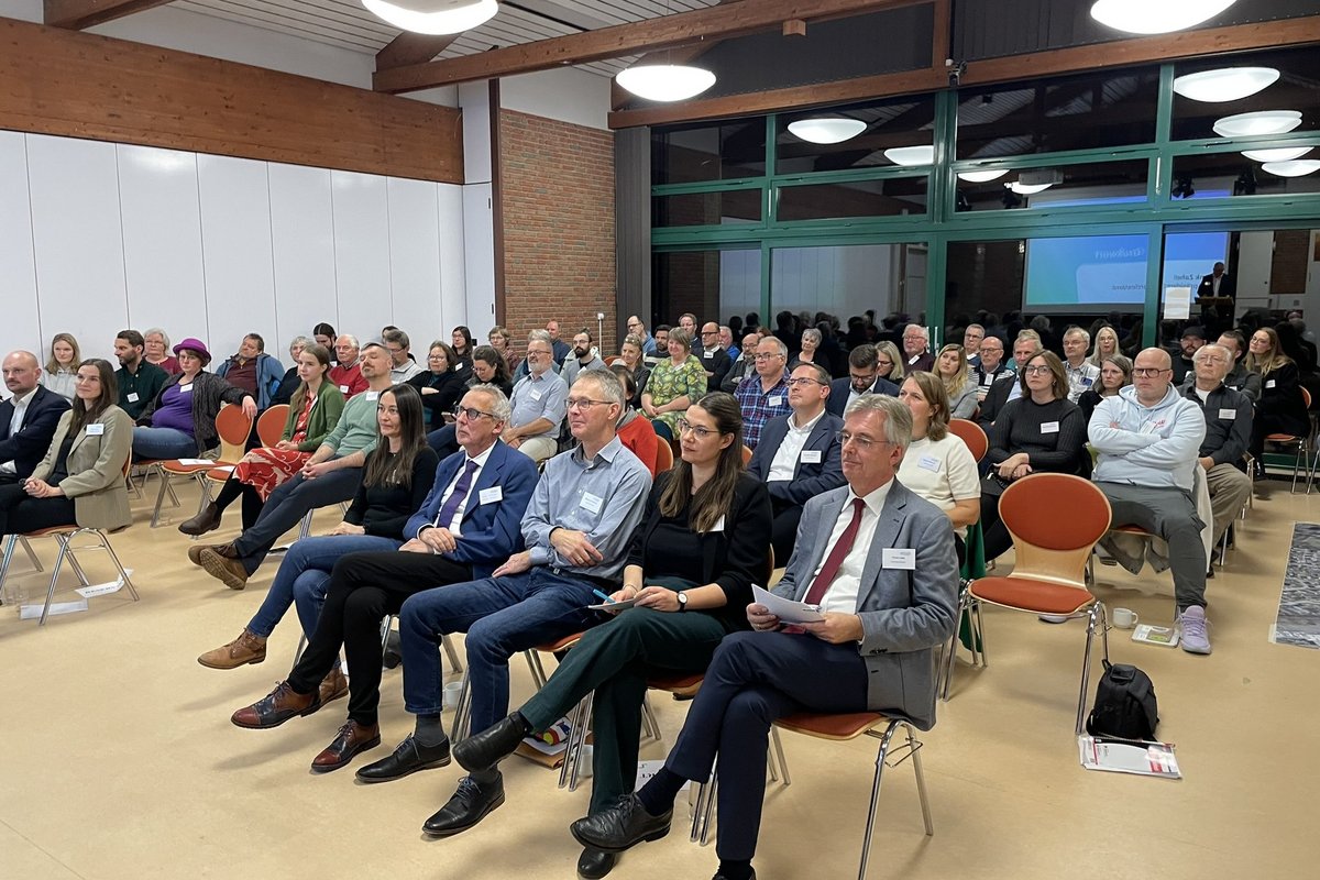 Ein Saal voller Menschen, die auf Stühlen sitzen.