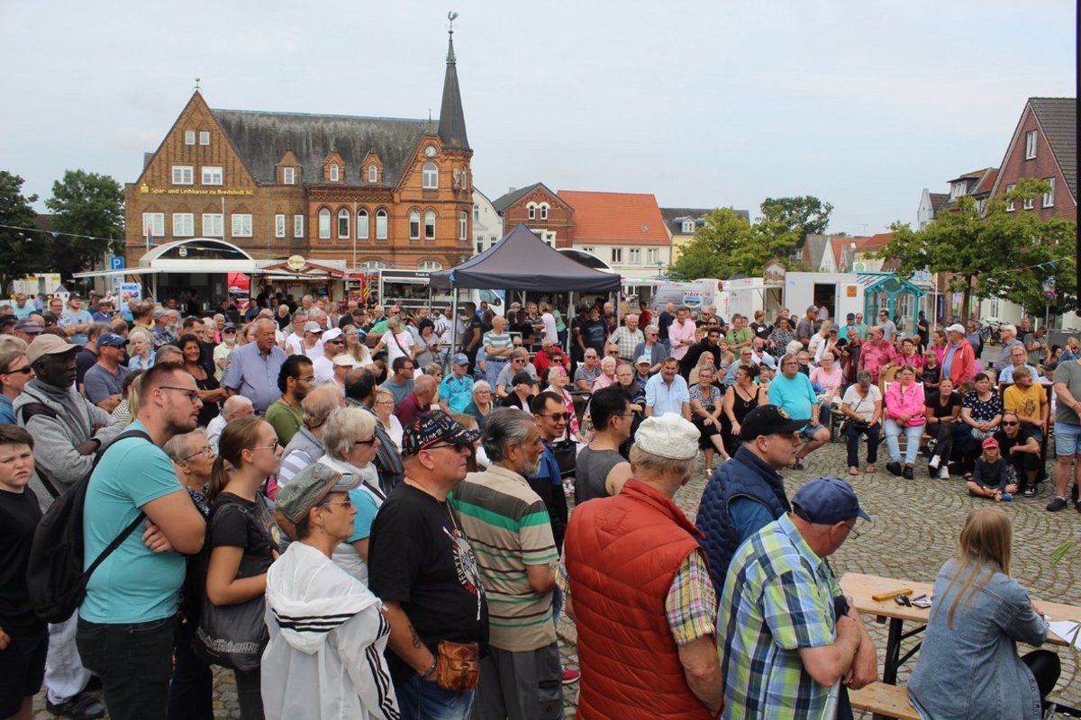 Viele Menschen stehen auf einem Marktplatz.