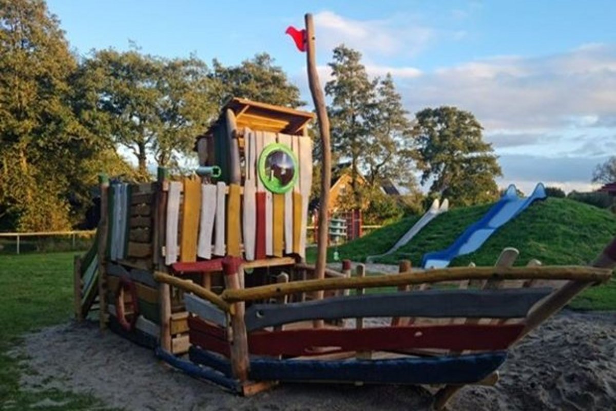 Ein Spielplatz mit einem Holzhaus in Form eines Schiffs