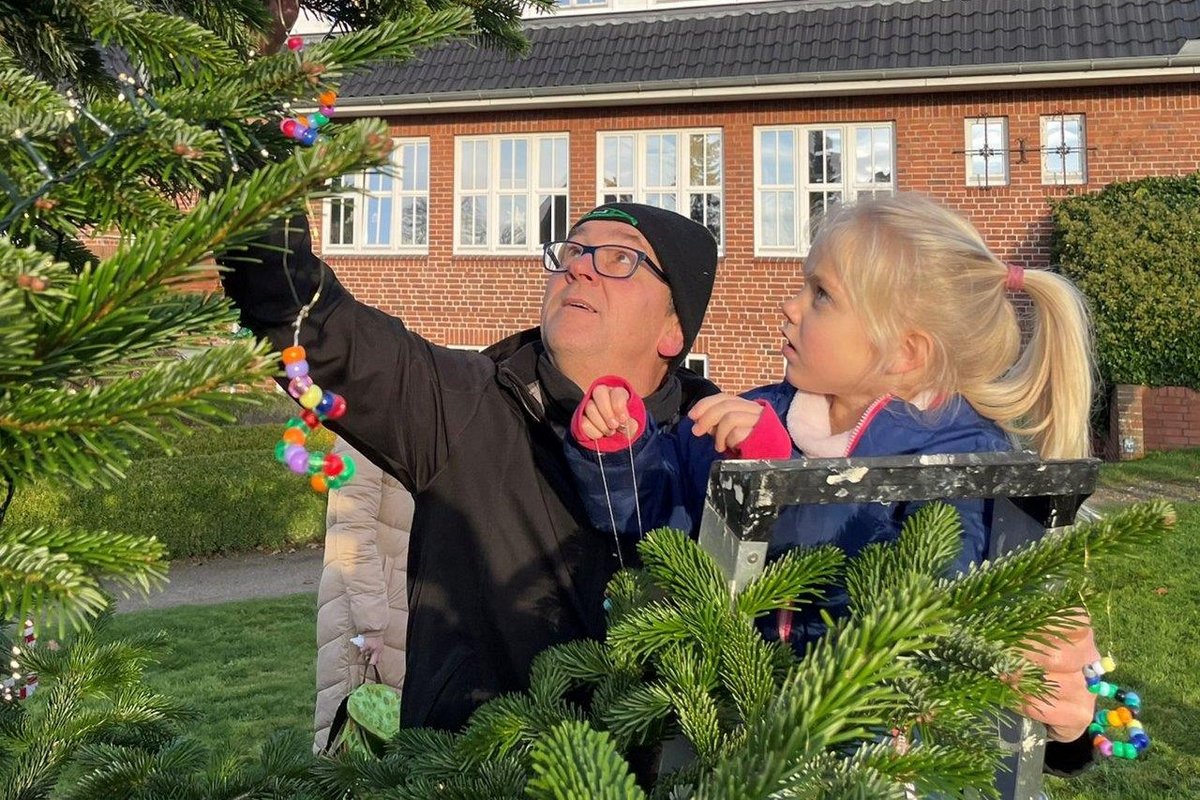 Ein Mann und ein Kind hängen Schmuck in einen Tannenbaum